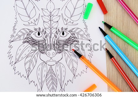 Adult anti stress coloring and soft tip pencils on wooden table, top view