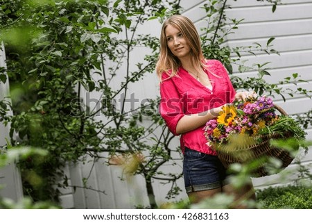 Young woman with basket of flowers in garden