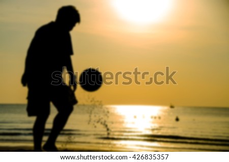 silhouette of man playing soccer on the beach with blue style