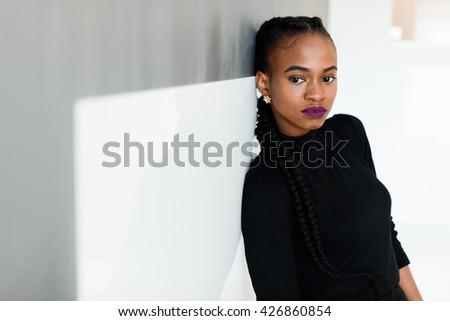 Side view of a serious african or black american woman looking at camera standing over white background