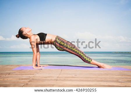 Woman doing yoga in the morning at the sea.