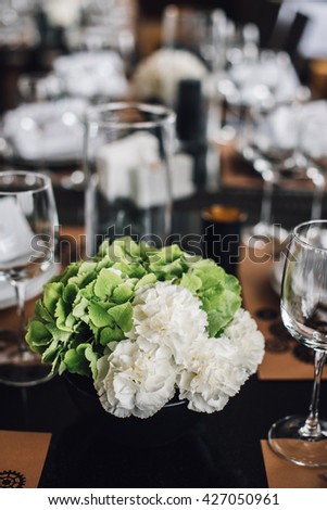 Wedding decor. Green and white hydrangea flowers in vase with cutlery and tableware on background. Reception. 