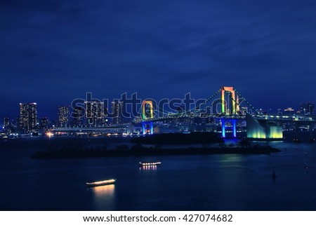 The night view of the Tokyo Rainbow Bridge and Tokyo Tower under a blue evening sky. Photoed at Odaiba, Tokyo, Japan.