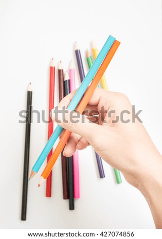 Color pencils in hand isolated on white background top view