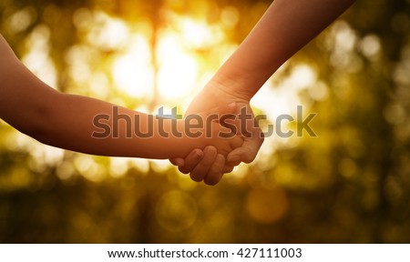 Close up of mother or older sister and a child hands at the sunset with copy space Royalty-Free Stock Photo #427111003