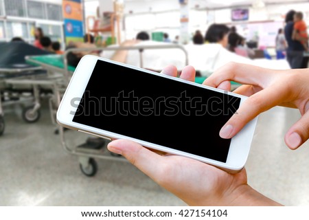 woman hand hold cell phone and touch screen smart phone, tablet,cellphone over blurred hospital background, emergency call on mobile phone concept.