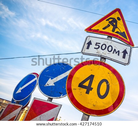Roadsigns over cloudy blue sky. Men at work, road under construction, speed limit