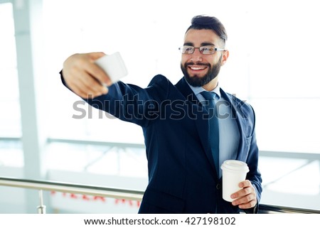 Posotove businessman taking selfie in office
