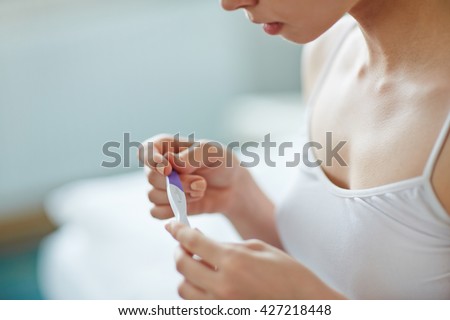 Young woman with pregnancy test in hands Royalty-Free Stock Photo #427218448