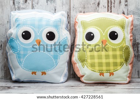 Colorful pillows with owl design on white wooden background