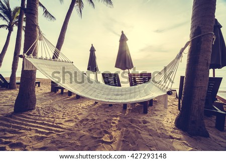 Empty hammock on the beach and sea with coconut palm tree at sunrise time - Vintage Filter