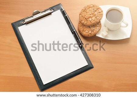 opened notebook with a cup of tea and flower on wooden table. Top view.
