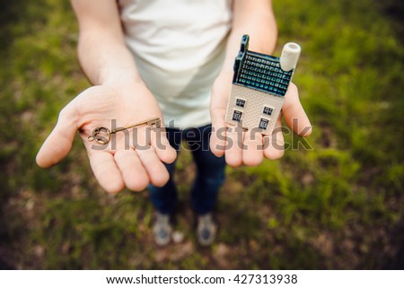 Key, House, Human Hand on a background of green grass. conceptual