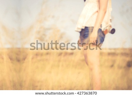 Blurred Girl standing in grass field with camera holding, vintage color filtered