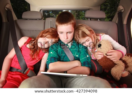 Kids watching a movie on a tablet in the back of a car