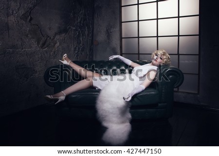 Beautiful woman with make-up skeleton lying on the sofa in a dark gothic interior