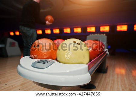 Bowling balls at bowl lift with ultraviolet lighting background player