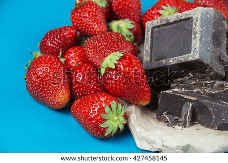 strawberry and natural black chocolate in confectionery plates, on a blue background. selective - Soft  focus