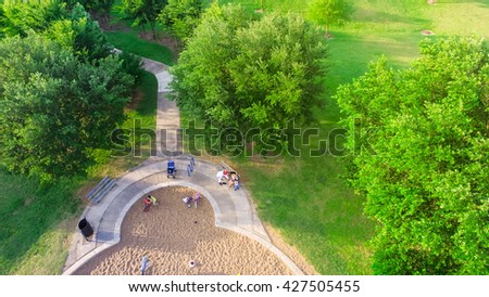 Aerial view of a big kid games playground at Harwin Park in Houston, Texas. An elevated view of slides and swings in the park surrounded by green trees. Children outdoor play and recreation concept.