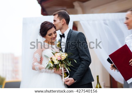 Portrait of handsome groom putting wedding ring on brides hand at registry office