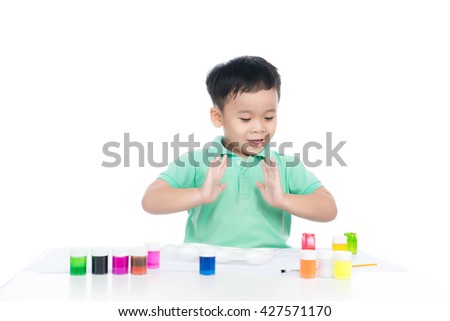 Happy cheerful child drawing with brush in album using a lot of painting tools isolated on a white background. Creativity concept.