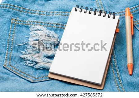 Notepad paper and pencil on blue jean texture.