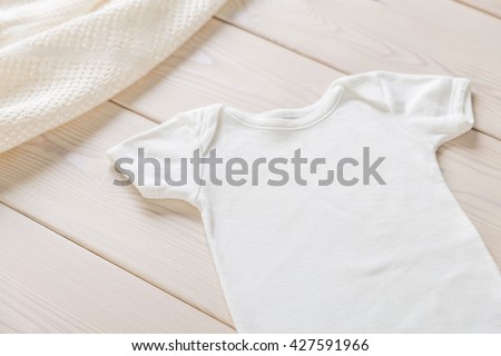 White baby shirt on wooden desktop. Mock up