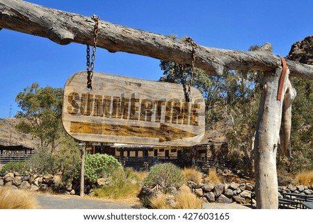 old wood signboard with arrow and text " summertime" hanging on a branch
