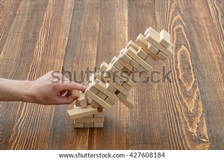 Hands of man pushed the brick and destroyed the tower. Janga. Close-up photo. Imbalance. Collapse and destruction. Mistake. Entertainment activity. Game of physical and mental skill. Removing blocks Royalty-Free Stock Photo #427608184