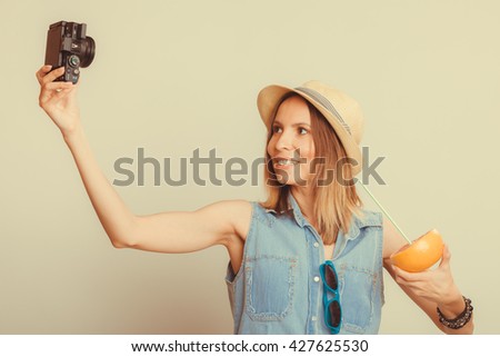 Happy tourist woman in straw hat taking selfie self picture with camera while holding grapefruit fruit in hand. Summer vacation holiday. Instagram filtered.