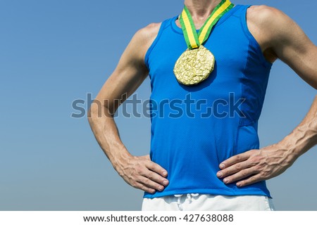 Athlete standing with gold medal hanging from a yellow and green ribbon against blue sky