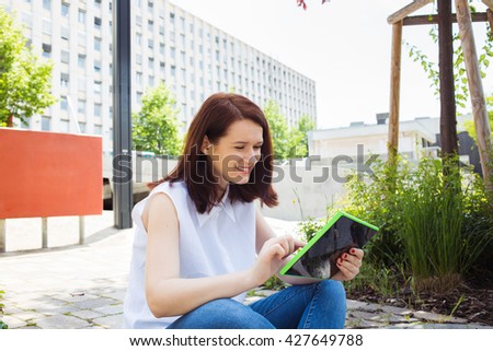 Smiling young woman student taping on tablet  using tablet in campus university.Young smiling student outdoors with tablet.Life style.City