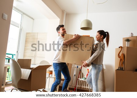 Young couple carrying big cardboard box at new home.Moving house. Royalty-Free Stock Photo #427668385
