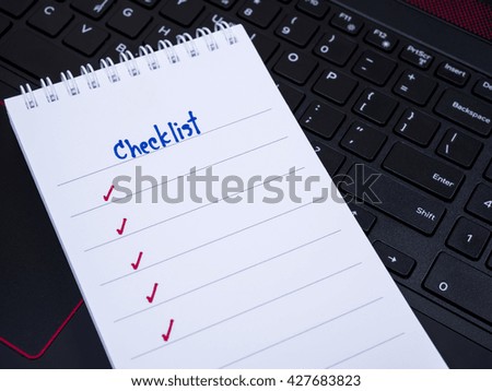 Handwriting Checklist on blank notebook with laptop keyboard background (Selective Focus)