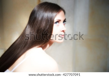 Beautiful young girl with long hair posing in bright light in a church. She is sad. probably she is thinking about human life