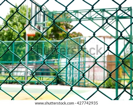 Metal fence with basketball court in the background 