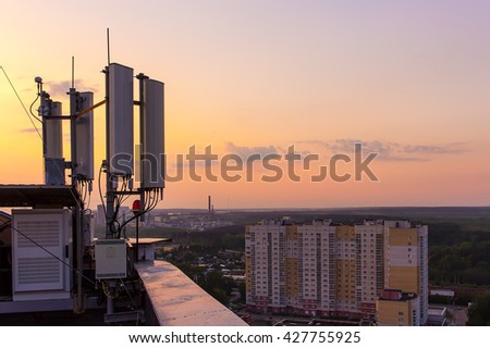 cellular communications tower on a background of the city and a beautiful sunset in summer Royalty-Free Stock Photo #427755925