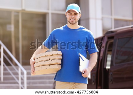 Young man holding pizza outside