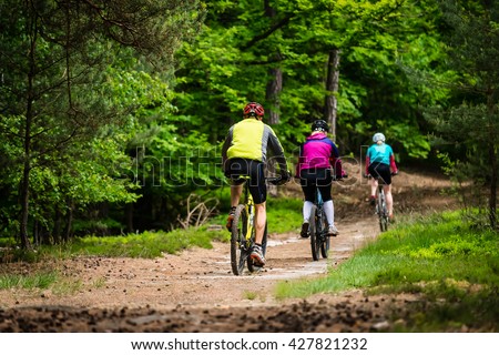 Group of cyclists on the forest trail - family trip on bikes in lush green nature Royalty-Free Stock Photo #427821232