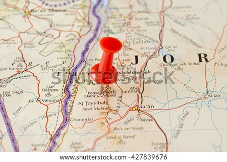 Petra marked on map with red pushpin. Selective focus on the word Petra and the pushpin. Pin is in an angle. Midground is sharp while foreground and background is blurry.