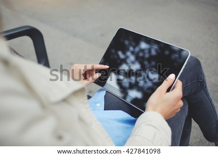 Closely image of hipster girl is chatting in social network via touch pad, while is relaxing in the fresh air during free time.Top view of woman`s hand is holding digital tablet with copy space screen