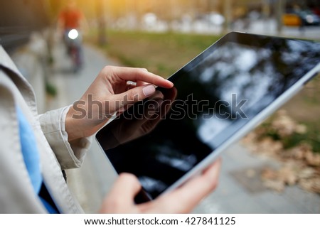 Closely image of hipster girl is working on portable computer with empty copy space screen. Close up of woman is navigating way in internet via digital tablet during walking in an unfamiliar city