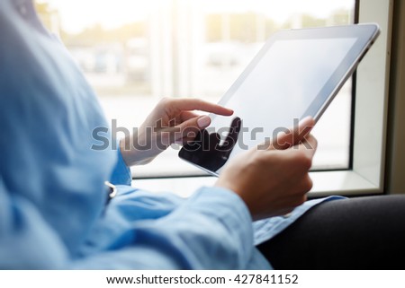 Closely image of teenager is playing games on portable touch pad, while is riding in the tram. Closeup of woman is checking e-mail in internet via digital tablet, while is sitting in public transport