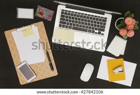 Flat lay photo of office desk with laptop and and lots of stationery objects
