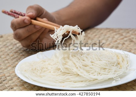 Idiyappam popular breakfast in South Indian, woman / female / girl eating with chopstick India. traditional Tamil, Kerala, Sri Lankan food consisting rice flour pressed into noodle form and steamed