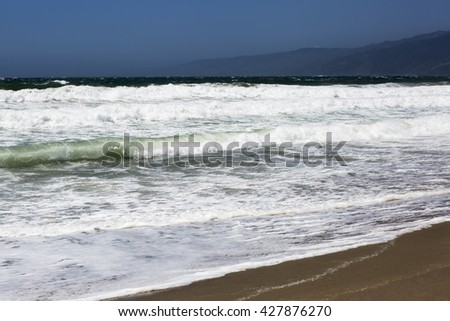 The waves of the Pacific ocean, the beach landscape. The ocean, mountains and blue sky in USA, Santa Monica. The ocean and waves during strong winds in United States, Santa Monica.