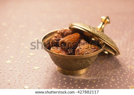 Ripened dates in a metal bowl. An important fruit in middle east. A golden bowl of dates. Royalty-Free Stock Photo #427882117