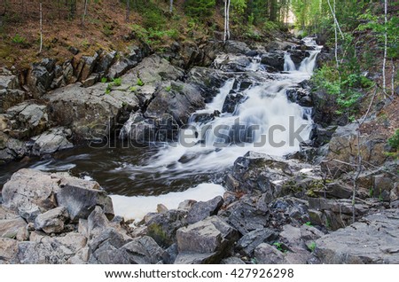 Waterfalls on a mountain river flowing through a mountain gorge on a summer evening