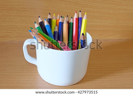 colored pencils in a glass on wooden background