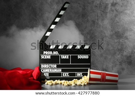 Clapper board and pop corn on wall background